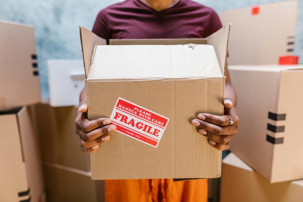 pexels-photo-7464708-7464708 A person holding a cardboard box labeled 'Fragile' during a moving process indoors.